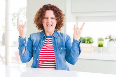 Kıvırcık saçlı, kot ceket giyen, çılgın bir ifadeyle bağıran, elleri havada rock sembolü yapan orta yaşlı bir kadın. Müzik yıldızı. Ağır müzik konsepti.