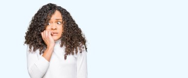 Kıvırcık saçlı genç güzel kadın boğazlı kazak giyen stresli ve sinirli elleri ile ağız Tırnakısırma. Anksiyete sorunu.