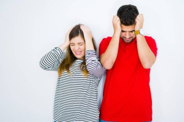 Genç güzel çift birlikte beyaz izole arka plan üzerinde baş ağrısı umutsuz muzdarip ve stresli çünkü ağrı ve migren. Eller baş üstünde.