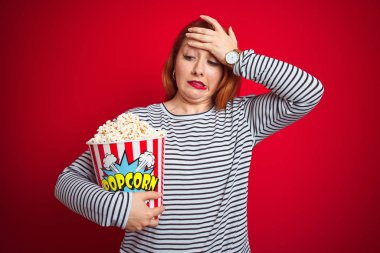 Genç, kızıl saçlı, patlamış mısırı kırmızı arka planda yiyen genç bir kadın. Kafa kafaya verip strese girmiş, utanç ve şaşkınlık dolu, sinirli ve hayal kırıklığına uğramış bir halde. Hata için korku ve üzüntü.