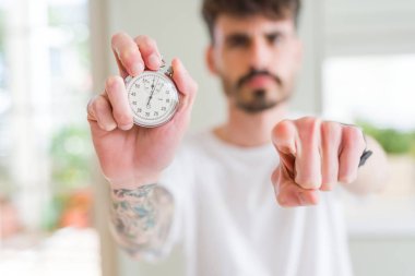 Genç adam kronometreyi kamerayı işaret ederek tutuyor ve sen, el işareti, ön taraftan pozitif ve kendinden emin bir hareket.