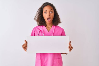 Genç Brezilyalı hemşire beyaz arka planda pankart tutuyor. Şaşırmış bir yüzle korkmuş ve korku ifadesinden heyecanlanmış.