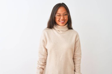 Balıkçı yaka kazak ve gözlük takan genç Çinli kadın izole edilmiş beyaz arka planda kameraya seksi bir ifadeyle bakıyor, neşeli ve mutlu bir yüzle..