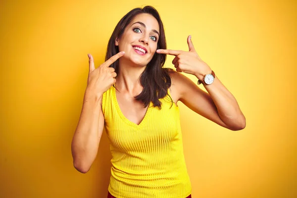 年轻美丽的女人穿着T恤 站在黄色孤立的背景上 笑容满面 用手指 牙齿和嘴指指指点点 牙齿健康概念 — 图库照片