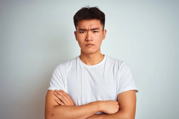 Tシャツを着た若いアジア系中国人男性は 孤立した白い背景の上に立って懐疑的で緊張し 両腕を組んで顔に否定的な表現をしています 負の人 — ストック写真