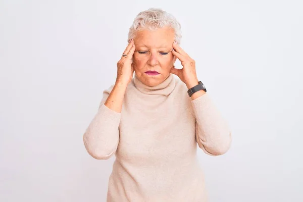 Senior grey-haired woman wearing turtleneck sweater standing over isolated white background with hand on headache because stress. Suffering migraine.