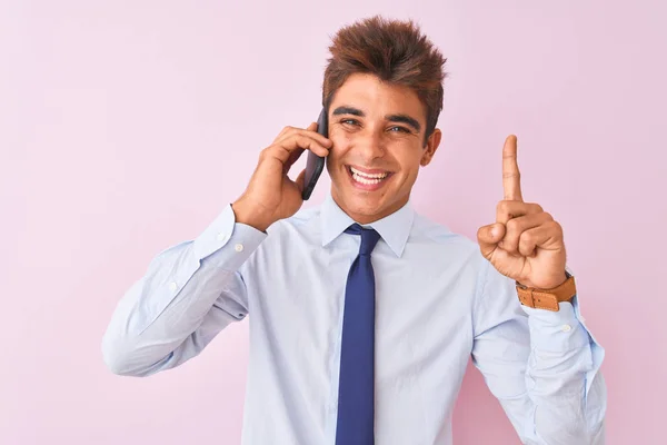 若いですハンサムなビジネスマンは幸せな顔をしたアイデアや質問を指差す指で驚いて隔離されたピンクの背景の上にスマートフォンで話して ナンバーワン — ストック写真