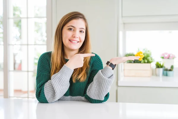Güzel, iri yarı, sıradan çizgili süveter giyen genç bir kadın kameraya hayret ediyor ve gülümsüyor..