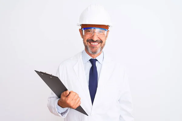 白い背景の上にクリップボードを保持ヘルメット眼鏡を身に着けているシニアエンジニア男幸せな顔立ちと笑顔で自信を持って笑顔を示す歯 — ストック写真