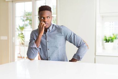 Beyaz tablo üzerinde yakışıklı Afrikalı Amerikalı adam vurguladı ve ağız ısırma çivi elleri ile gergin bakıyor. Anksiyete sorunu.
