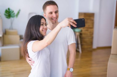 Karton kutular etrafında yeni evde mesaj ile kara tahta tutan katta duran genç güzel çift