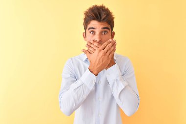 Soyutlanmış sarı arka planda zarif gömlekler giyen genç yakışıklı iş adamı yanlışlıkla ağızlarını kapatarak şok etti. Gizli konsept.