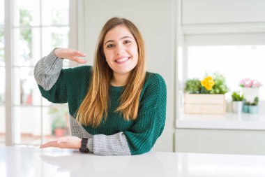 Güzel, iri yarı, sıradan çizgili süveter giyen, elleri büyük ve büyük bir işaret gösteren, ölçü sembolü olan genç bir kadın. Kameraya bakıp gülümsüyor. Ölçüm konsepti.