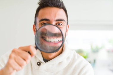 Yakışıklı adam büyüteç kullanarak, komik yüzler yapıyor