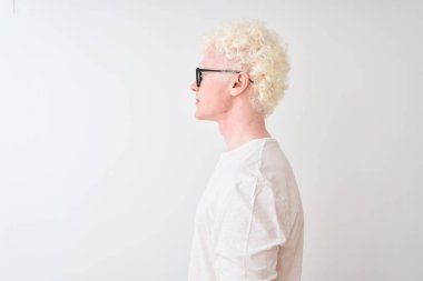 Tişört giyen ve gözlüklü genç albino bir adam. İzole edilmiş beyaz arka planda duruyor. Yan tarafa bakıyor..