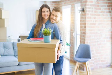 Güzel genç çift yeni bir ev, yeni bir dairede mutlu tutan karton kutular gülümseyen hareket
