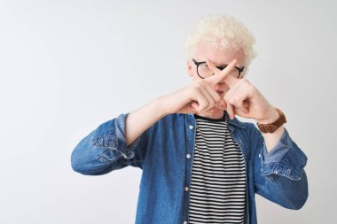 Kotlu gömlek ve gözlüklü genç albino adam izole edilmiş beyaz arka planda reddedilme ifadesi olumsuz işaret yapıyor.
