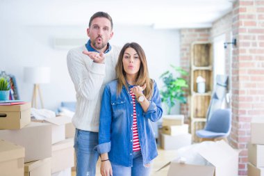 Genç ve güzel bir çift, yeni evlerinde karton kutuların etrafında durmuş kameraya bakıp havada öpüşüyorlar ve çok güzel ve seksiler. Aşk ifadesi.