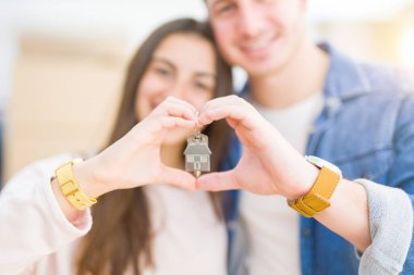 Güzel genç çift aşık ve yeni ev, yeni bir daireye hareket mutlu gülümseyen anahtarları gösteren sarılma