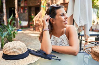 Genç ve güzel bir kadın tropikal bir restoranda oturuyor ve yaz tatilinin tadını çıkarıyor.