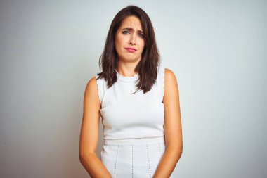 İzole edilmiş beyaz arka planda duran elbise giyen genç ve güzel bir kadın üzgün ve endişeli, sinirli ve korkmuş bir şekilde ağlıyor. Üzücü ifade.