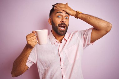 Genç Hintli bir adam gömleğini giymiş pembe arka planda dikilip kahve içiyor. Elleri başının üstünde, utanç ve şaşkınlık dolu, sinirli ve hayal kırıklığına uğramış bir halde. Hata için korku ve üzüntü.