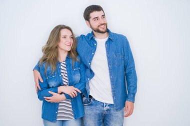 Genç ve güzel bir çift, beyaz soyutlanmış arka planda yan yana durup gülümsüyor ve düşüncelere dalıyorlar..