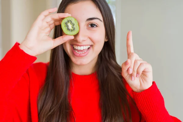 半分新鮮な緑のキウイを食べる美しい若い女性は 幸せな顔で指を指すアイデアや質問に驚きました ナンバーワン — ストック写真