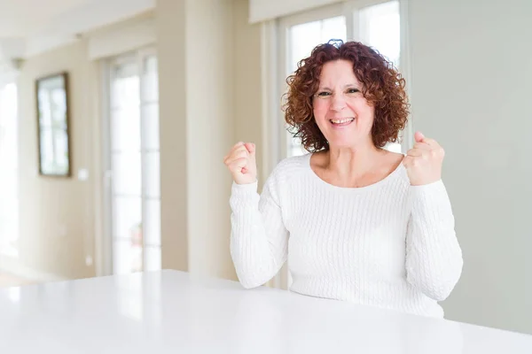 自宅で白いセーターを着た美しい先輩女性は 腕を上げて目を開けて成功に驚き 驚きました 勝者のコンセプト — ストック写真