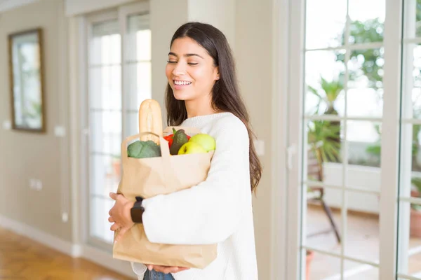 Schöne junge Frau lächelt und hält eine Papiertüte voller frischer — Stockfoto