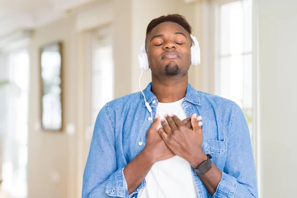 目を閉じて感謝のジェスチャーで胸に微笑む音楽を聴くヘッドフォンを着たアフリカ系アメリカ人男性 健康の概念 — ストック写真