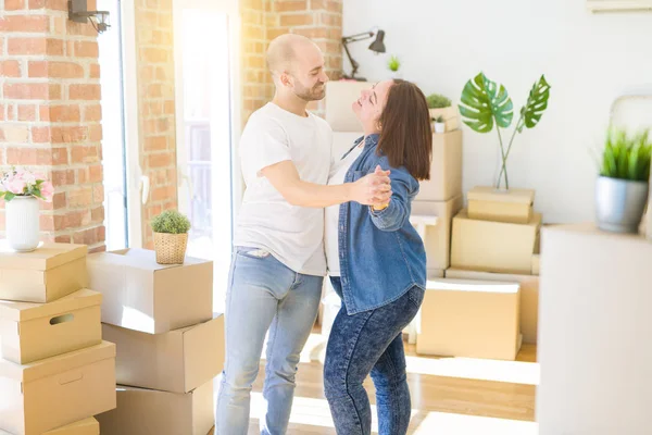 Casal jovem dançando em torno de caixas de papelão na nova casa, celebra — Fotografia de Stock