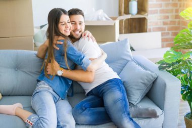 Kanepede aşık güzel çift sarılmak, çok mutlu yeni ev için heyecanlı gülümseyen