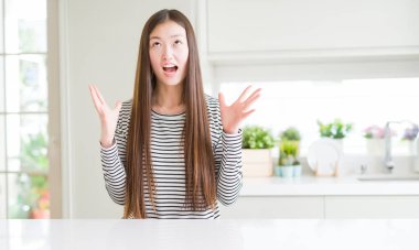 Güzel Asyalı kadın çizgili kazak deli ve deli çığlık giyiyor ve agresif ifade ve silah ile bağırdı kaldırdı. Hayal kırıklığı kavramı.