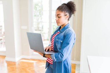 Genç Afro-Amerikan kız ayakta çalışma acımak yüz ciddi düşünüyorum üstünde kendine güvenen bir ifade ile dizüstü bilgisayar kullanarak