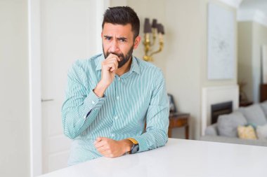 Evde yakışıklı İspanyol adam vurguladı ve ağız ısırma çivi elleri ile gergin bakıyor. Anksiyete sorunu.