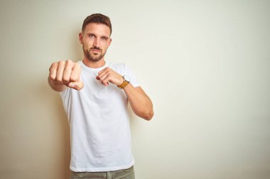 İzole arka planda rahat beyaz t-shirt giyen genç yakışıklı adam, saldırgan ve öfkeli saldırı, tehdit ve şiddet mücadele yumruk Punch