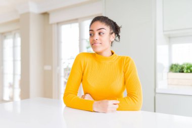 Afro saçlı, sıradan sarı bir kazak giyen güzel Afro-Amerikalı kadın gülümseyip yan tarafa bakıyor ve şöyle düşünüyor:.