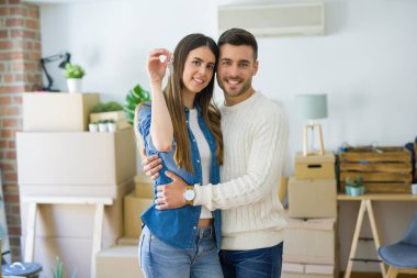 Genç çift yeni bir eve hareket, yeni dairenin anahtarlarını gösteren aşk sarılmak çok mutlu gülümseyen