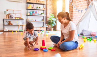 Güzel öğretmen ve küçük çocuk anaokulunda çember taşaklarıyla piramit inşa ediyor.
