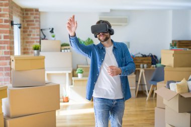 Yeni bir eve hareket karton kutular etrafında bir simülasyon oyunu oynarken sanal gerçeklik gözlük giyen genç adam