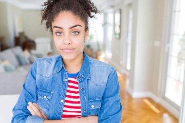 Yüzünde ciddi ifade ile rahat rahat denim ceket giyen afro saçlı güzel genç Afro-Amerikan kadın. Basit ve çapraz silah ile doğal