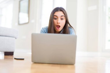 Şaşırtıcı bir yüz ile şok korkuyor laptop kullanarak yerde döşeme güzel genç kadın, korkuyor ve korku ifadesi ile heyecanlı