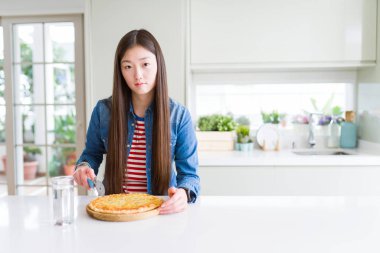 Güzel Asyalı kadın, satranç pizzası yiyor ve kesiyor. Zeki bir yüz ifadesiyle, ciddi ciddi düşünüyor.
