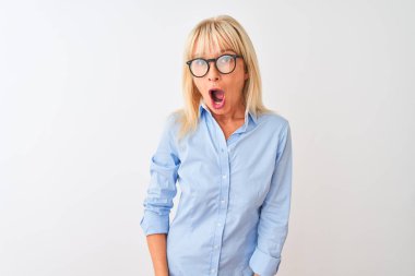 Orta yaşlı iş kadını zarif gömlek ve gözlük takıyor beyaz arka planda korku ve şaşkınlık dolu bir ifade, korku ve heyecan dolu bir yüz..