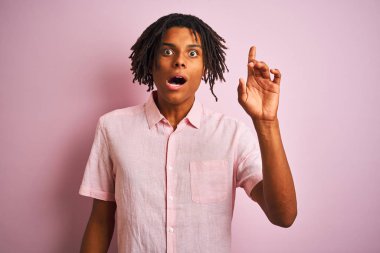 Zarif tişörtlü Afro-Amerikan bir adam izole edilmiş pembe arka planda duruyor ve başarılı bir fikri işaret ediyor. Heyecanlı ve mutlu. Bir numara..
