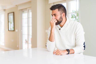 Evde rahat beyaz süveter giyen yakışıklı, gergin ve ağzı tırnak yiyen elleri olan bir İspanyol. Endişe sorunu.