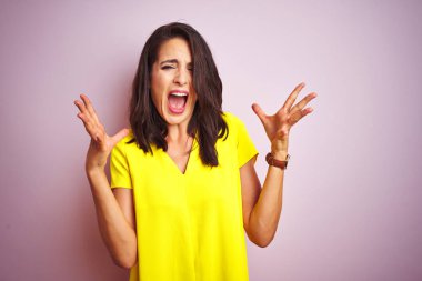 Sarı tişört giyen genç ve güzel bir kadın pembe izole edilmiş arka planda duruyor. Kolları havada ve gözleri kapalı heyecanla haykırarak başarının çılgınlığını kutluyorlar. Kazanan konsept