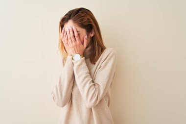 Şık balıkçı yaka kazak giyen kızıl saçlı kadın izole edilmiş beyaz arka planda dikiliyor. Üzücü yüz ifadesini ellerle kapatıyor ve ağlıyor. Depresyon kavramı.