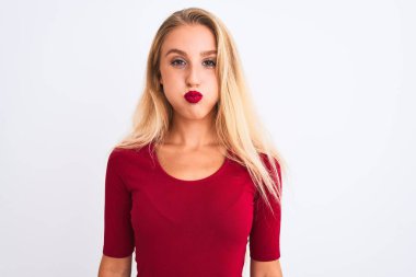 Kırmızı tişört giyen genç ve güzel bir kadın izole edilmiş beyaz arka planda durup komik yüzlü yanakları şişiriyor. Havayla şişmiş ağız, çılgın bir ifade..